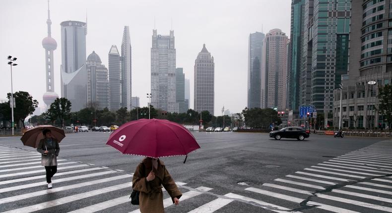 SHANGHAI, CHINA - FEBRUARY 24: A woman crosses a pedestrian crossing in wet weather in the Shanghai's financial district (Lujiazui) on February 24, 2018 in Shanghai, China.Vincent Isore/IP3