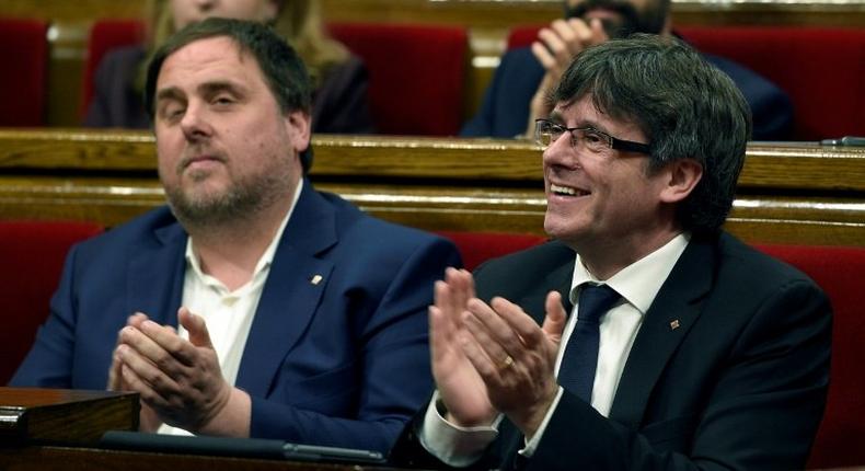 President of the Catalan regional Government Carles Puigdemont (R) and Catalan regional vice-president, Oriol Junqueras applaud after voting the Catalan government's 2017 budget at the Parliament of Catalonia on March 22, 2017 in Barcelona