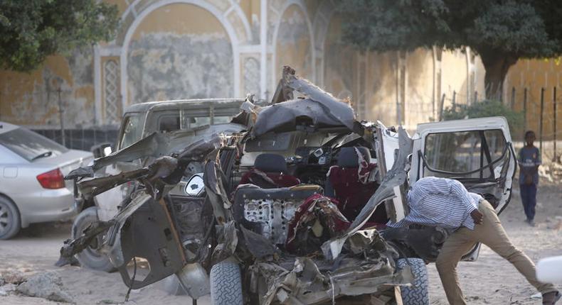 A Somali police officer looks inside the wreckage of a car destroyed when Islamist militants opened fire on government officials in a car and then a car bomb exploded, according to police and a spokesman for Mogadishu's mayor, in Yaqshiid district of Somalia's capital Mogadishu, April 18, 2016.