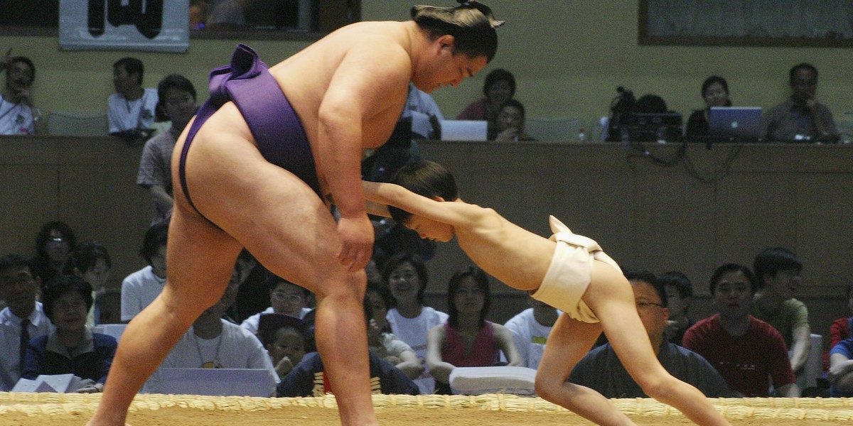 Mały chłopiec próbuje "walczyć" z profesjonalnym zapaśnikiem sumo podczas ceremonii otwarcia zawodów w Pekinie