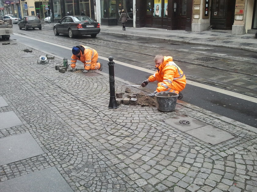 Robotnicy ustawiają słupki na chodniku przy ul. Ruskiej