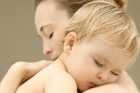 Mother holding sleeping baby boy (9-12 months), close-up