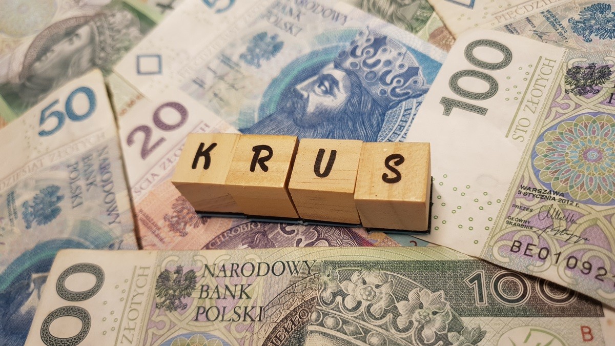 Kostki z napisem KRUS leżące na polskich banknotach 100, 20 i 50 zł.
