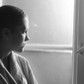 Young depressed cancer patient standing in front of hospital window