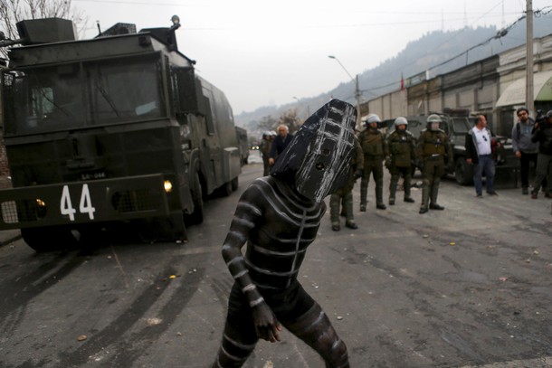 A demonstrator, depicting a person of the extinct indigenous tribe Selknam, attends a protest markin