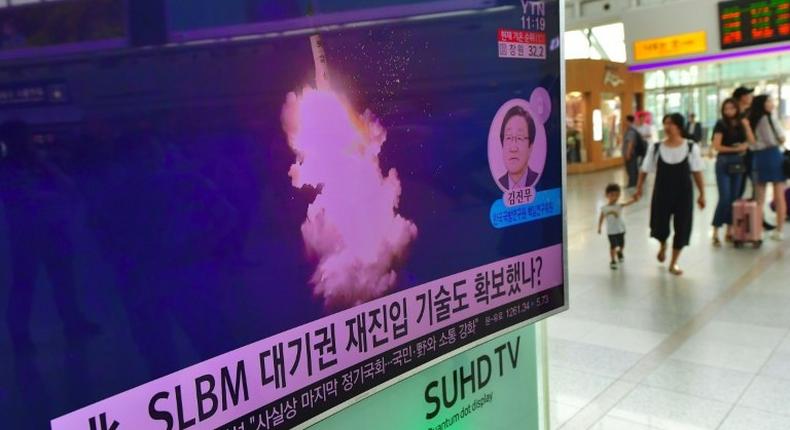 This file photo from August 25, 2016 shows people walking past a television screen at a railway station in Seoul reporting news of a North Korean submarine-launched ballistic missile test