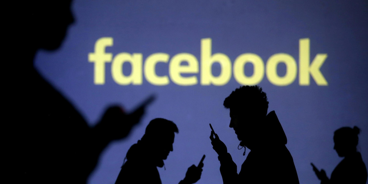 FILE PHOTO: Silhouettes of mobile users are seen next to a screen projection of Facebook logo in this picture illustration
