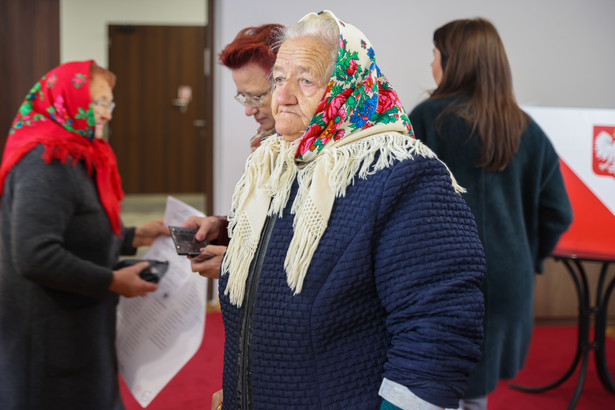 Wybory 2023. Kobieta w tradycyjnej łowickiej chuście głosuje w lokalu wyborczym w Głuchowie