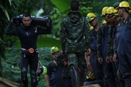 A diver carries an oxygen tank as he leaves the Tham Luang cave complex, where 12 boys and their soc