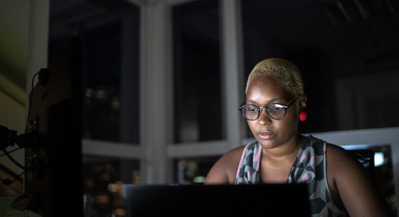 Black professional working late, woman on laptop