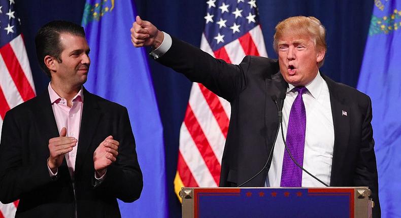 Donald Trump Jr. (L) looks on as his father, Donald Trump, waves after speaking at a caucus night watch party at the Treasure Island Hotel & Casino in Las Vegas, Nevada.