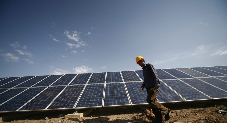 A construction worker walks past solar panels installed in Xinjiang, China.VCG /Getty Images