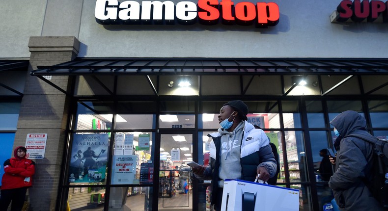 A man stands outside of a GameStop store with a new PlayStation 5 game console.
