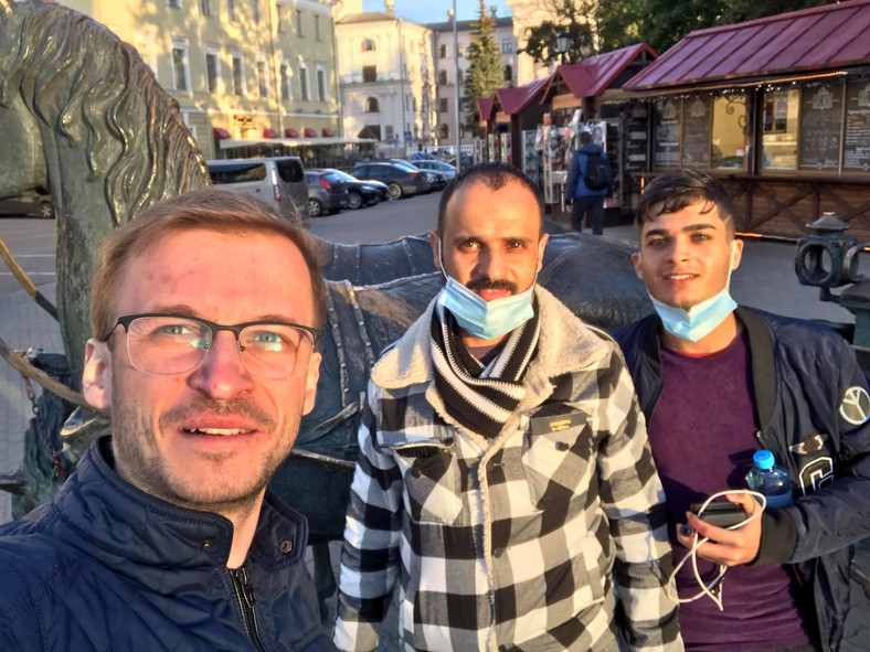 Pavel Chuduk z dwoma imigrantami z Iraku na ulicy w Mińsku.