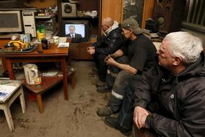 Workers watch a TV broadcast of Russian President Putin address to the Federal Assembly at an auto r