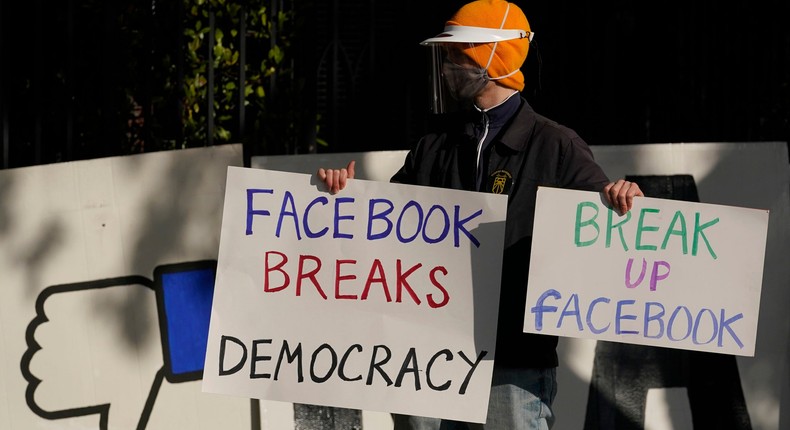 Protestor in front of Facebook sign