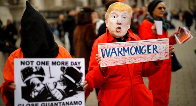 A protester holds up a placard, dressed as US President Donald Trump in Trafalgar Square during a demonstration against the threat of war on Iran, in central London on January 11, 2020