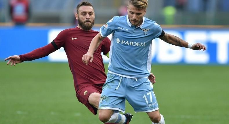 Roma's midfielder from Italy Daniele De Rossi (L) tackles Lazio's forward from Italy Ciro Immobile during the Italian Serie A football match SS Lazio vs AS Roma on December 4, 2016