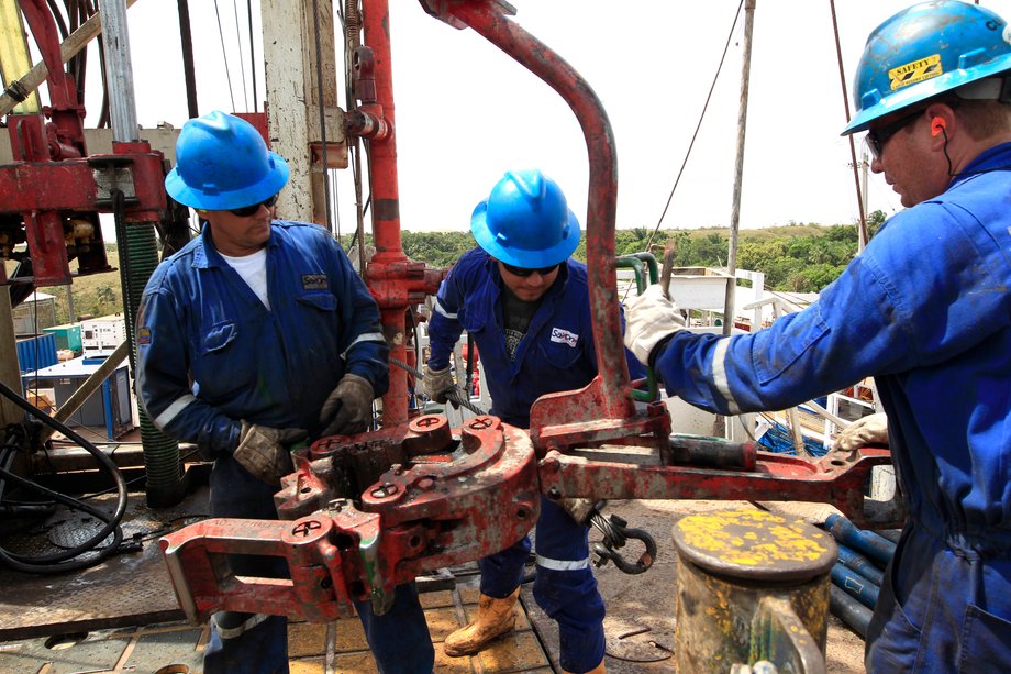 Employees of the Canadian Pacific Rubiales Petroleum Company stand next to oil excavation pipes at Campo Rubiales field in Meta, eastern Colombia.