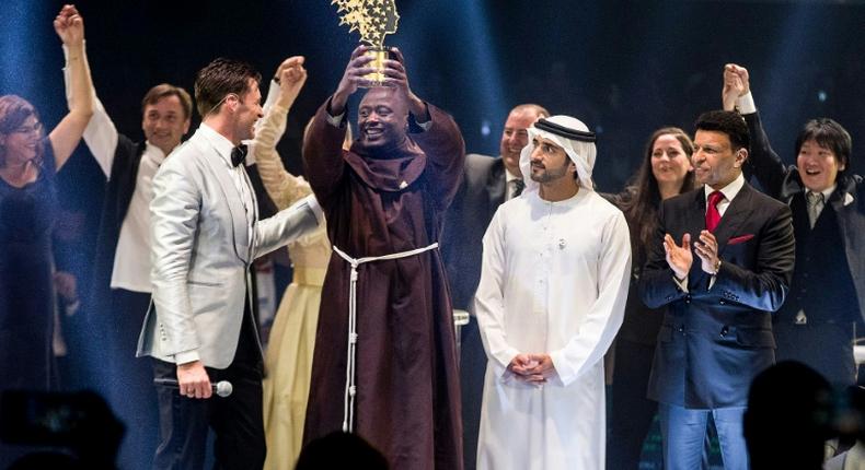 This picture provided on March 24, 2019 by the Global Education and Skills Forum of the Varkey Foundation, shows Kenyan teacher Peter Tabichi (C) in Dubai holding up the trophy for world's best teacher which comes with a prize of $1 million