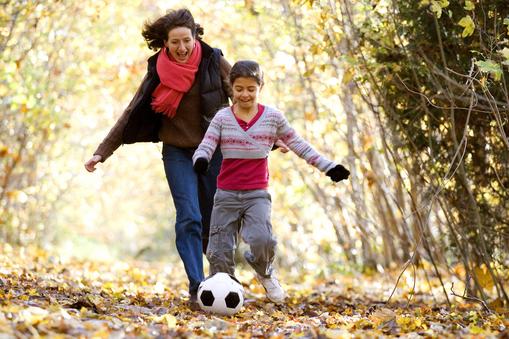 Mid adult woman and her daughter playing with a soccer ball