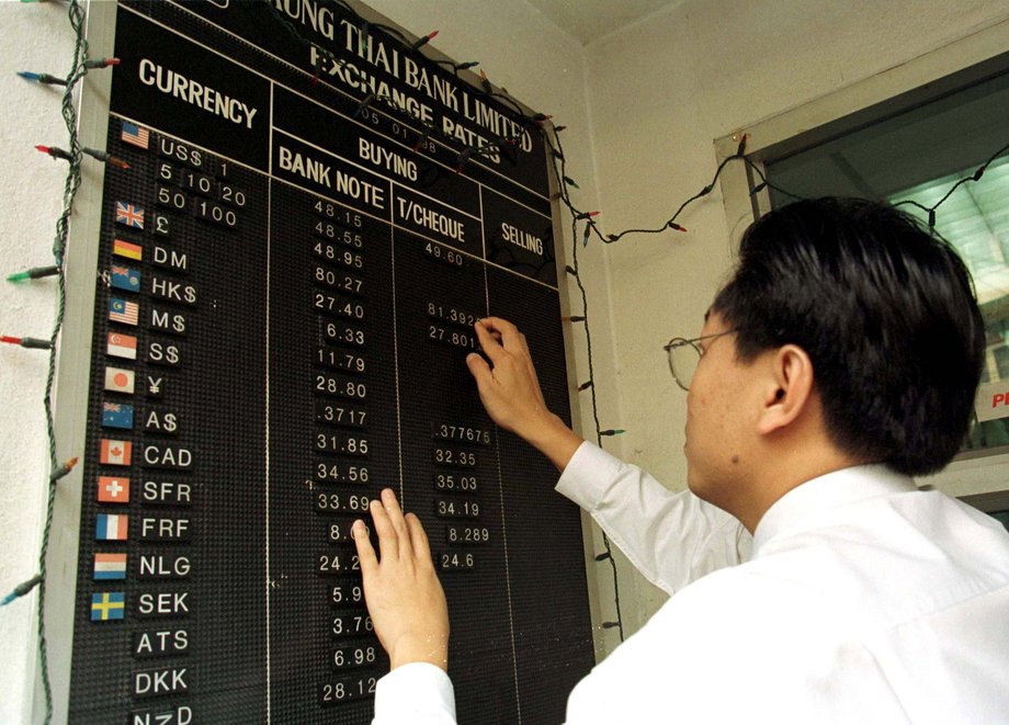 A bank employee changes the rate of foreign currencies outside a bank in central Bangkok on January 5. Thai markets began the new year with a hangover as the Thai baht crumbled to a record low onshore and the stock market took another pounding. The baht has now lost almost 50% of its value against the American dollar.