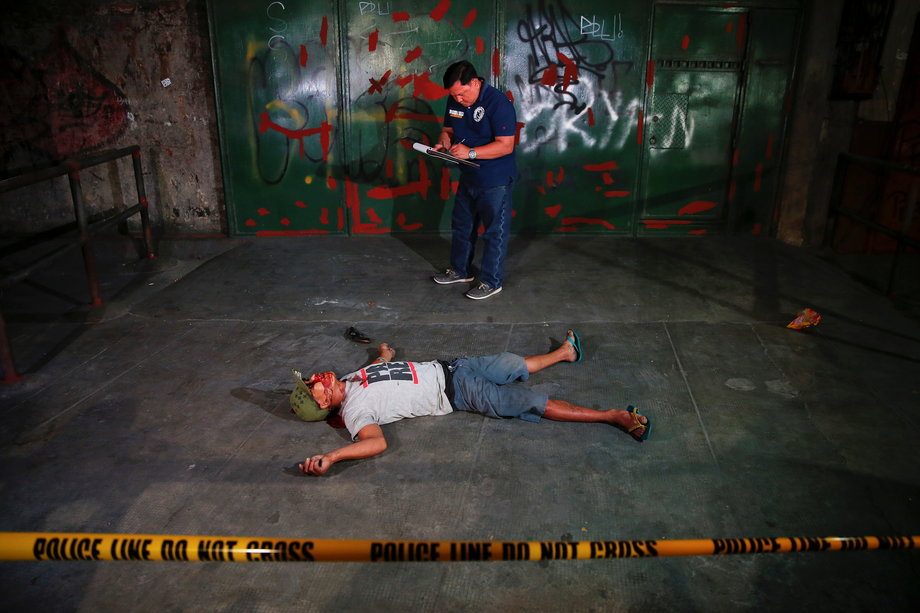 An investigator takes notes next to the body of a man killed in a shoot-out with police in Manila, Philippines, early on October 21, 2016. According to the police, sachets containing substance believed to be the drug shabu (metamphetamine hydrochloride) were found in the man's pockets.