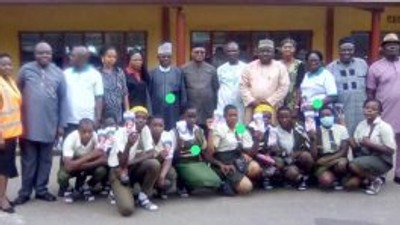 Dr Mathew Ashikeni, Director, Special duties, FCT Health and Human Services Secretariat and  Mrs Eze pose for a picture with students of Government Secondary School, Life camp, Gwarimpa Abuja where the event held. [NAN]