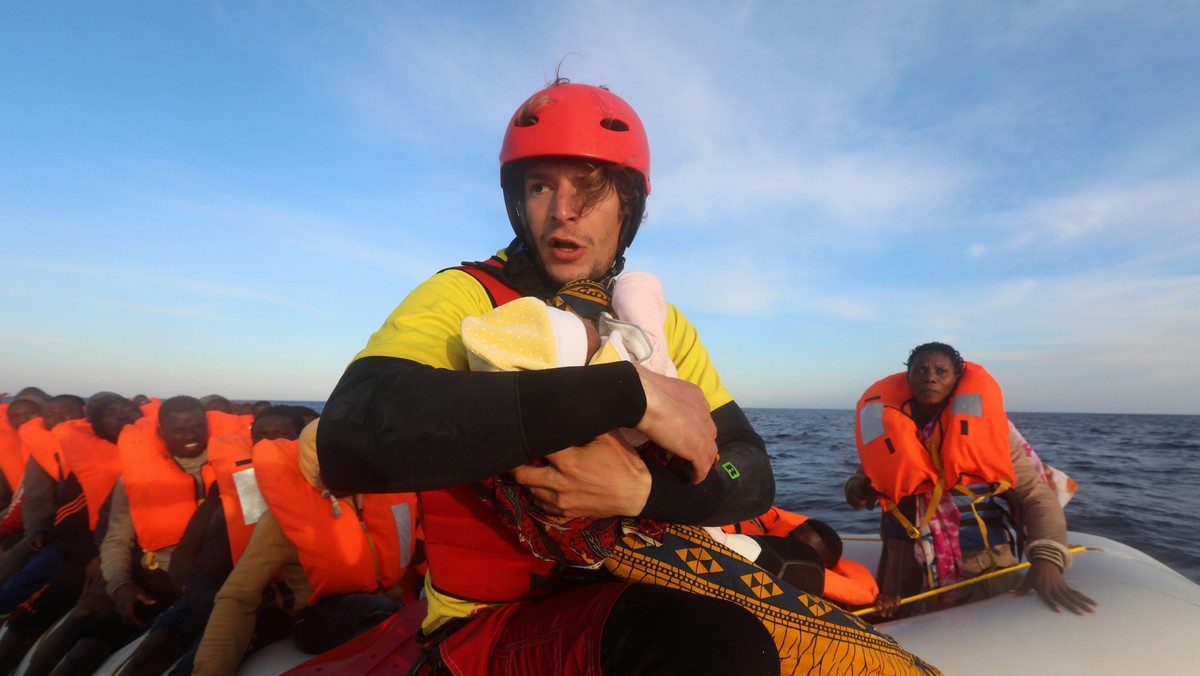 Spanish rescuer Daniel Calvelo carries a four-day-old baby girl into a RHIB, during a search and res