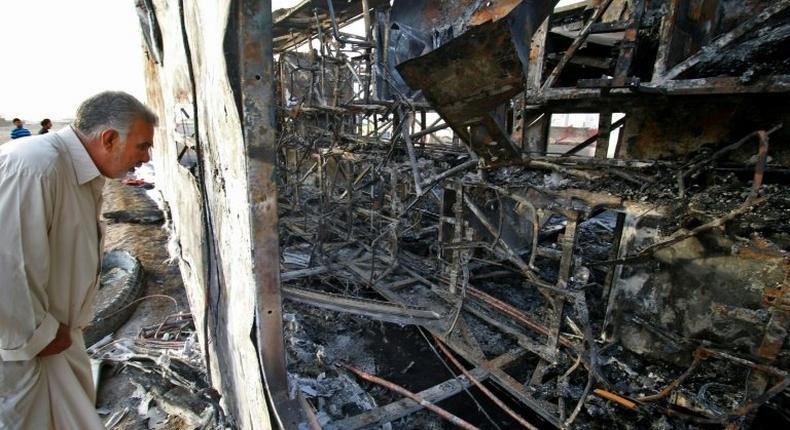 An Iraqi man inspects the wreckage of a bus that was damaged in a car bomb attack, in the southern Iraqi city of Basra on May 20, 2017