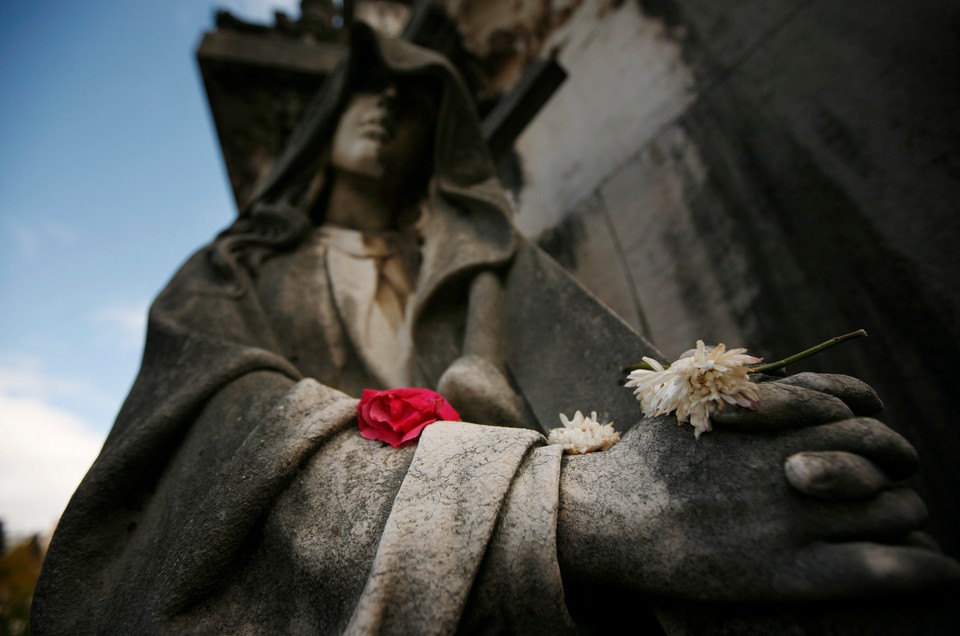 Flowers lie on a statue at the Prazeres cemetery in Lisbon