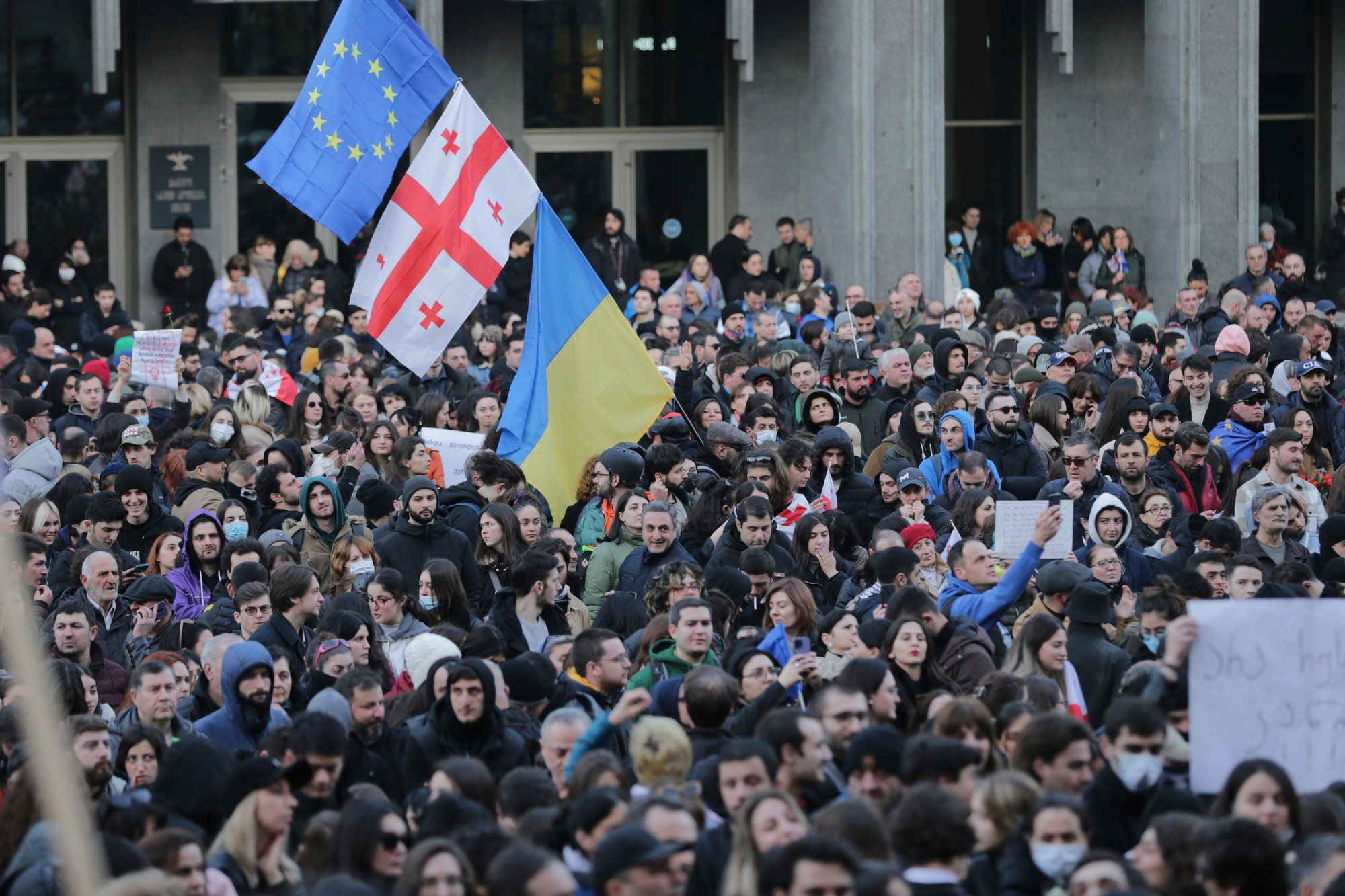 Protestujúci sa zhromažďujú s americkými, gruzínskymi, ukrajinskými vlajkami a vlajkami EÚ pred budovou gruzínskeho parlamentu 8. marca 2023 v Tbilisi.