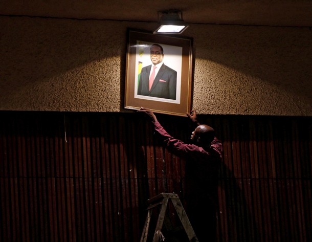 An official puts up a portrait of Zimbabwe?s President Emmerson Mnangagwa ahead of a meeting of the 