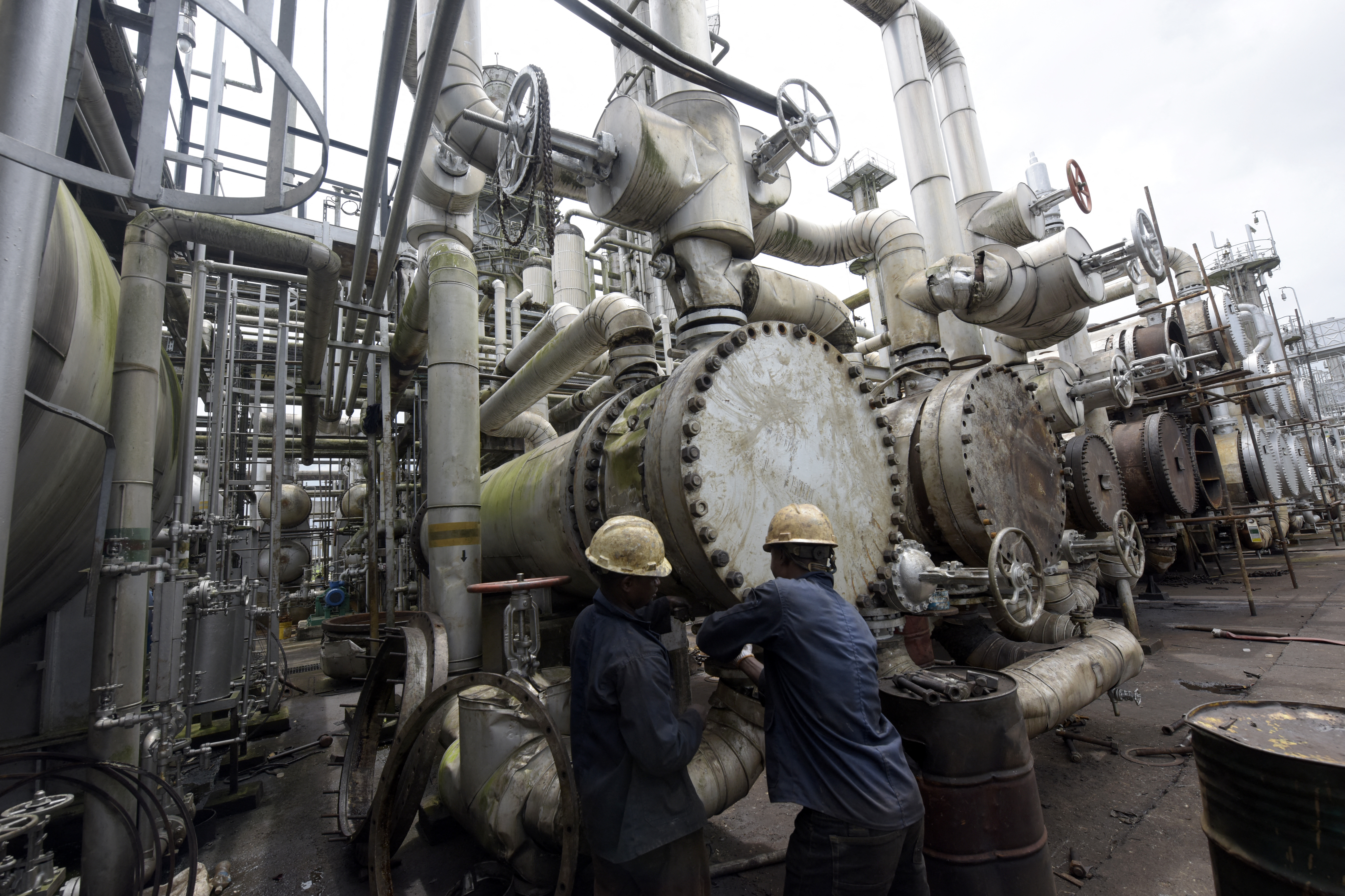 A picture taken on September 16, 2015 shows workers trying to tie a pipe of the first refinery in Nigeria, which was built in 1965 in oil rich Port Harcourt, Rivers State. [PIUS UTOMI EKPEI/AFP via Getty Images]