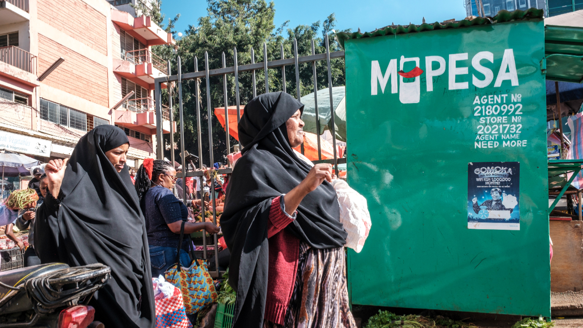 Women pass a retail kiosk offering Safaricom Plc M-Pesa mobile money services in Nairobi, Kenya, on Tuesday, Nov. 7, 2023. Safaricom report earnings on Nov. 9. [Photo: Eduardo Soteras Jalil/Bloomberg via Getty Images]