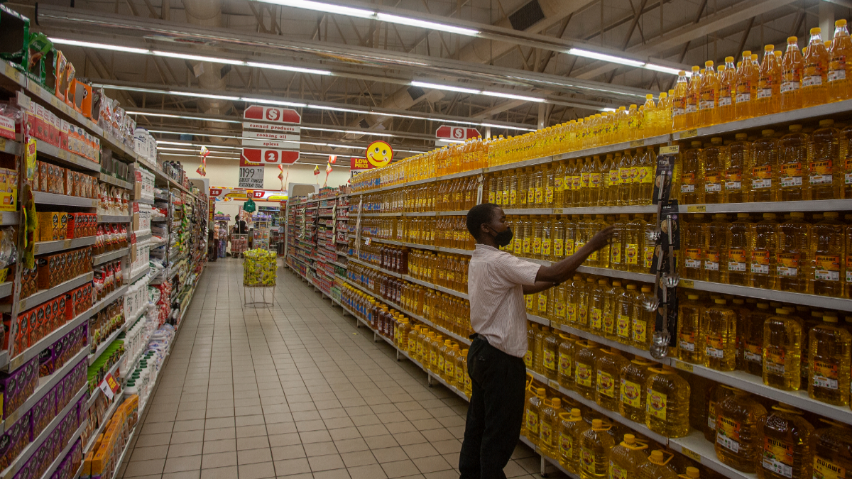 A Shoprite worker arranges cooking oil on shelves in Lilongwe, Malawi, March 16, 2022. [Photo by AMOS GUMULIRA/AFP via Getty Images]