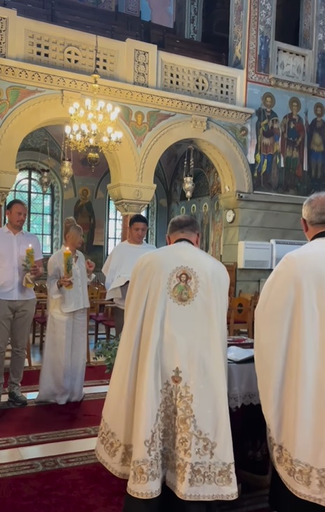 Anamaria Prodan și Ronald Gavril, în postura de nași de botez. Îmbrăcați în alb, au devenit părinții spirituali ai unui băiețel
