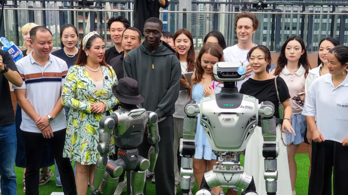 Khaby Lame, Italian-Senegalese influencer and TikTok's most-followed content creator, interacts with humanoid robots during during his visit in Qianhai Cooperation Zone on September 19, 2025 in Shenzhen, Guangdong Province of China. [Photo by VCG/VCG via Getty Images]