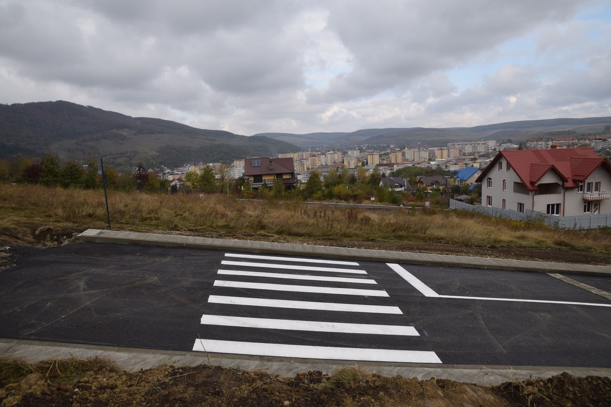 Stradă asfaltată și marcată, care duce spre nicăieri. Are trecere de pietoni și indicator "stop" pe un deal