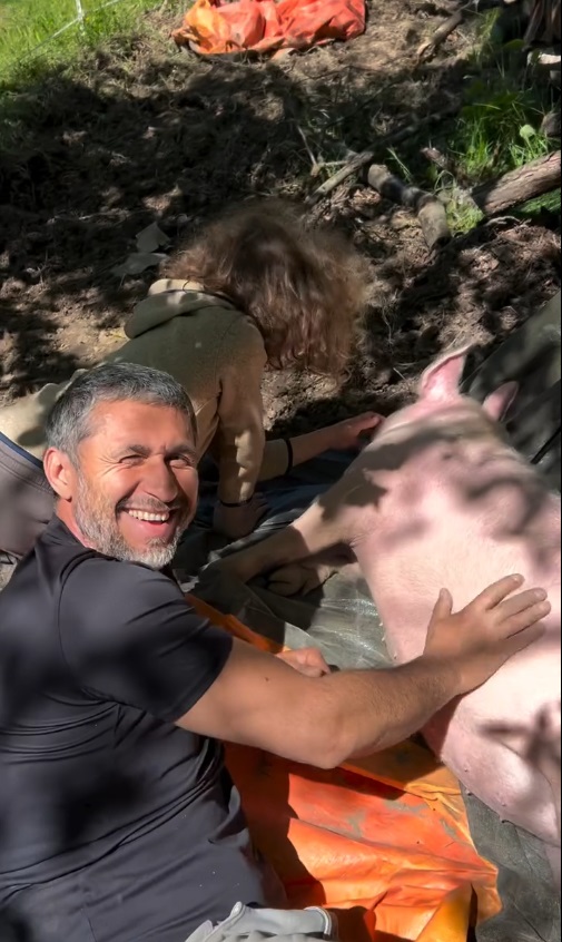 Dragoș Bucur și băiețelul Kadri, surprinși când se joacă cu porcul familiei, în grădina casei. Dana Nălbaru i-a filmat, când a luat o pauză de la sădit răsaduri