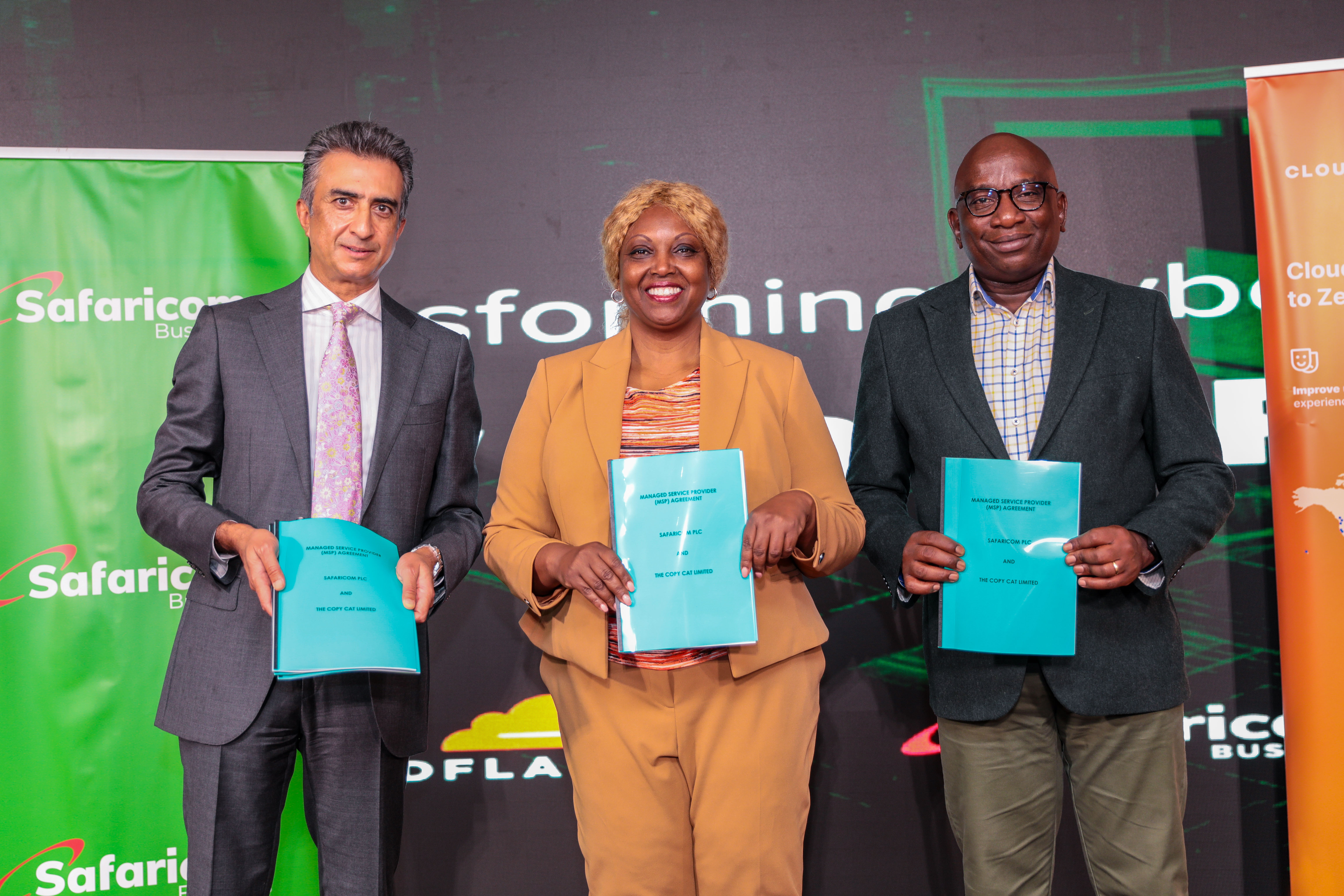 Cynthia Kropac (C), Chief Enterprise Business Officer at Safaricom, is accompanied by Michael Mutiga (L), Chief Business Development & Strategy Officer at Safaricom, and Vishal Patel (R), Managing Director at Copycat Limited. They are photographed after signing a Memorandum of Understanding during the launch of Safaricom's partnership with Cloudflare, aimed at providing integrated cybersecurity solutions. The event took place at the Michael Joseph Center in Nairobi, Kenya, on October 15, 2024.