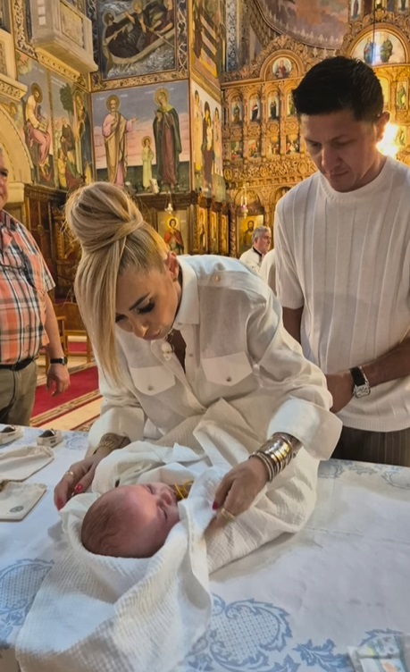 Anamaria Prodan și Ronald Gavril, în postura de nași de botez. Îmbrăcați în alb, au devenit părinții spirituali ai unui băiețel