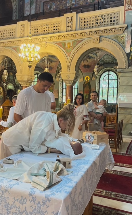Anamaria Prodan și Ronald Gavril, în postura de nași de botez. Îmbrăcați în alb, au devenit părinții spirituali ai unui băiețel