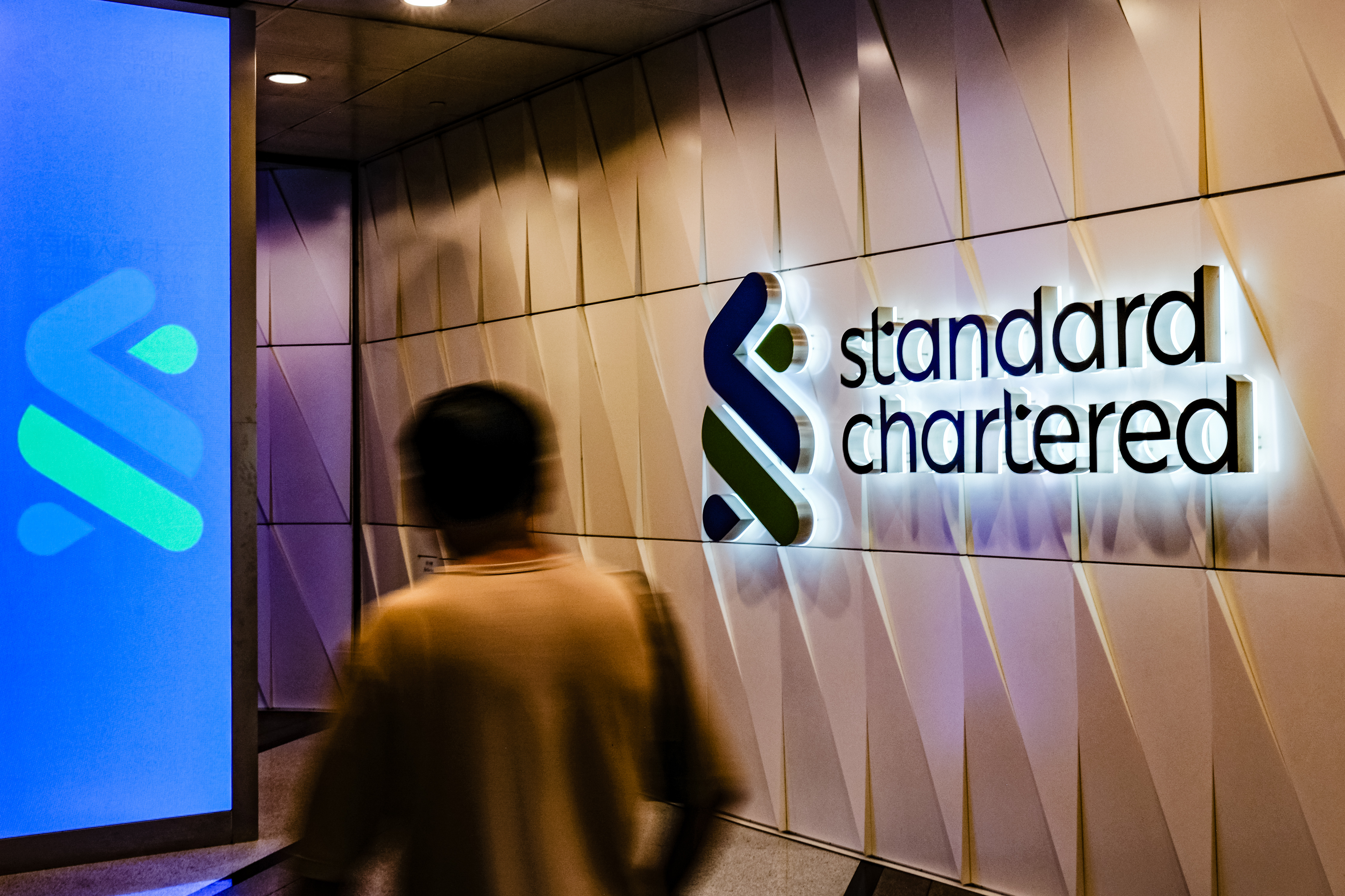 A man walks past the Standard Chartered sign on October 31, 2025. [Photo by Sawayasu Tsuji/Getty Images]