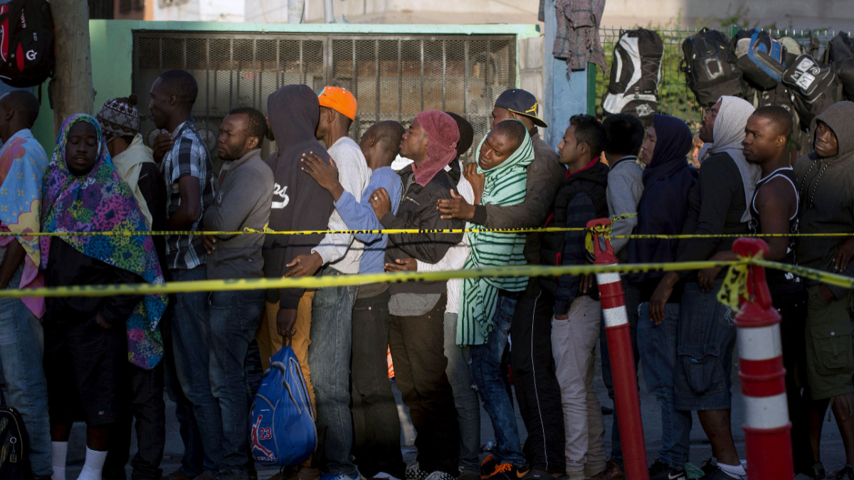 Haitian and African migrants seeking asylum in the United States, queue at Mexico's migration office in the Mexican border city of Tijuana, in Baja California, on October 3, 2016. [Photo credit should read GUILLERMO ARIAS/AFP via Getty Images]
