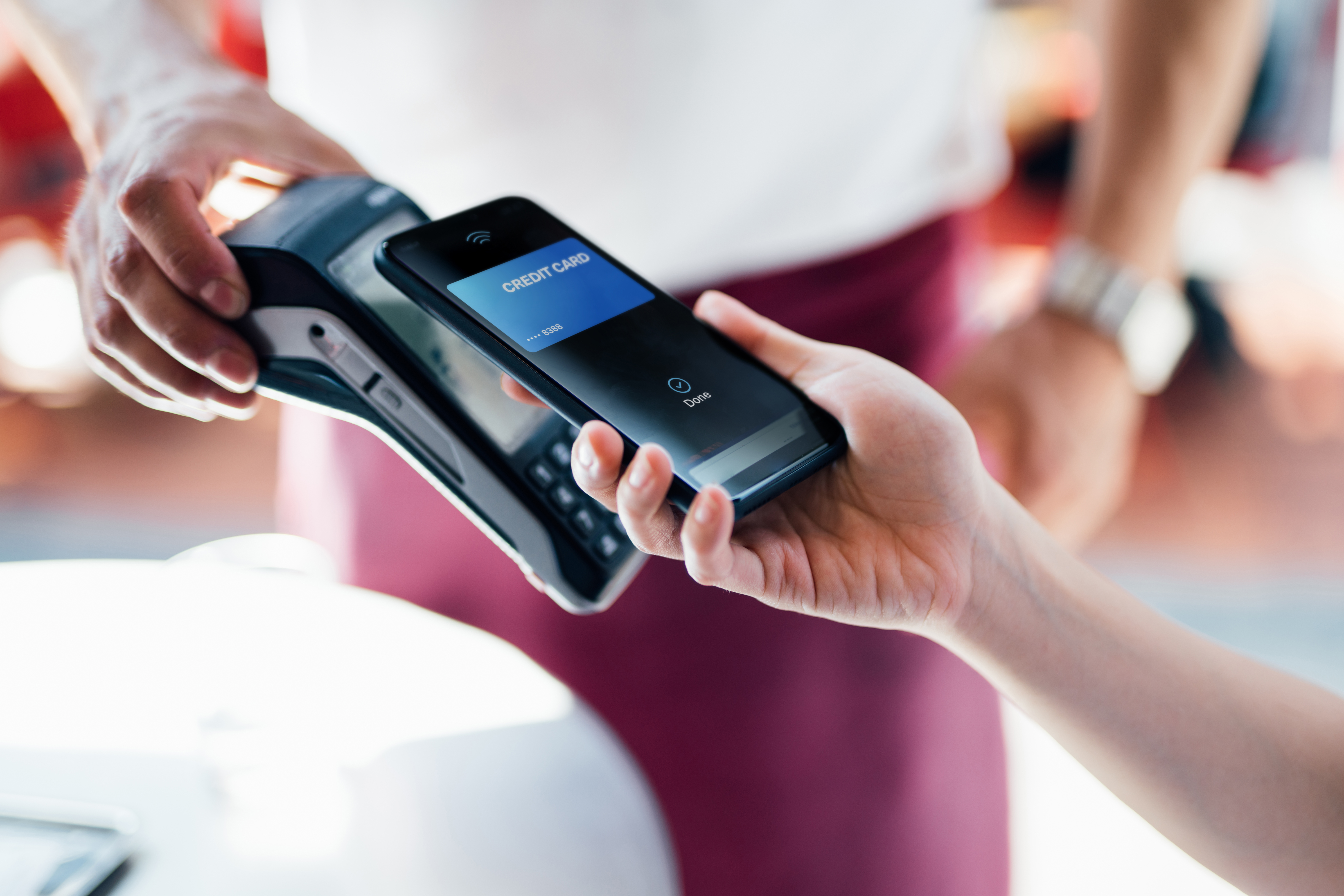 Close-up shot of a female hand using her smart phone to scan and pay for a bill at the restaurant during the day. Contactless payment, Technology Concept. [Stock Photo via Getty Images]