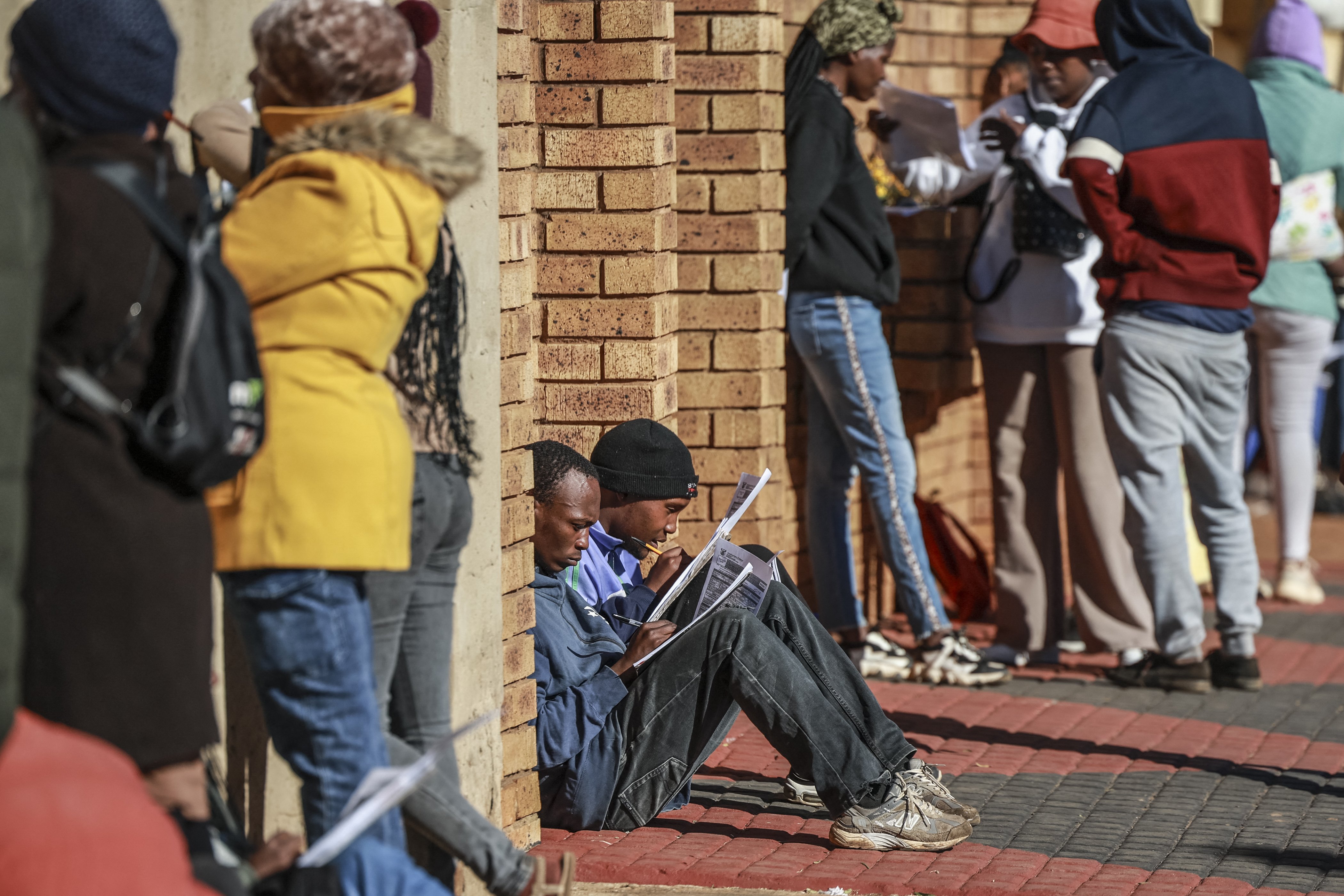 Unemployed people fill in the Department of Unemployment and Labour work seeking registration forms while queuing with others at a centre in Chiawelo, Soweto on June 27, 2025, as they look to be added into the departmentÕs data base. [Photo by PHILL MAGAKOE/AFP via Getty Images]