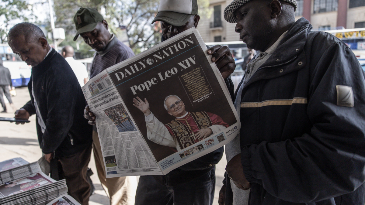 Pedestrians read the Daily Nation newspaper with the front page bearing headlines and images announcing the newly elected Pope Leo XIV, Robert Prevost, in downtown Nairobi, on May 9, 2025. [Photo by SIMON MAINA / AFP) (Photo by SIMON MAINA/AFP via Getty Images]