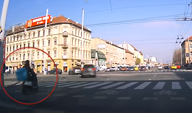 A piros lámpával mit sem törődve hajtott a forgalmas kereszteződésbe a robogós futár Budapesten: durva baleset lett a vége - videó