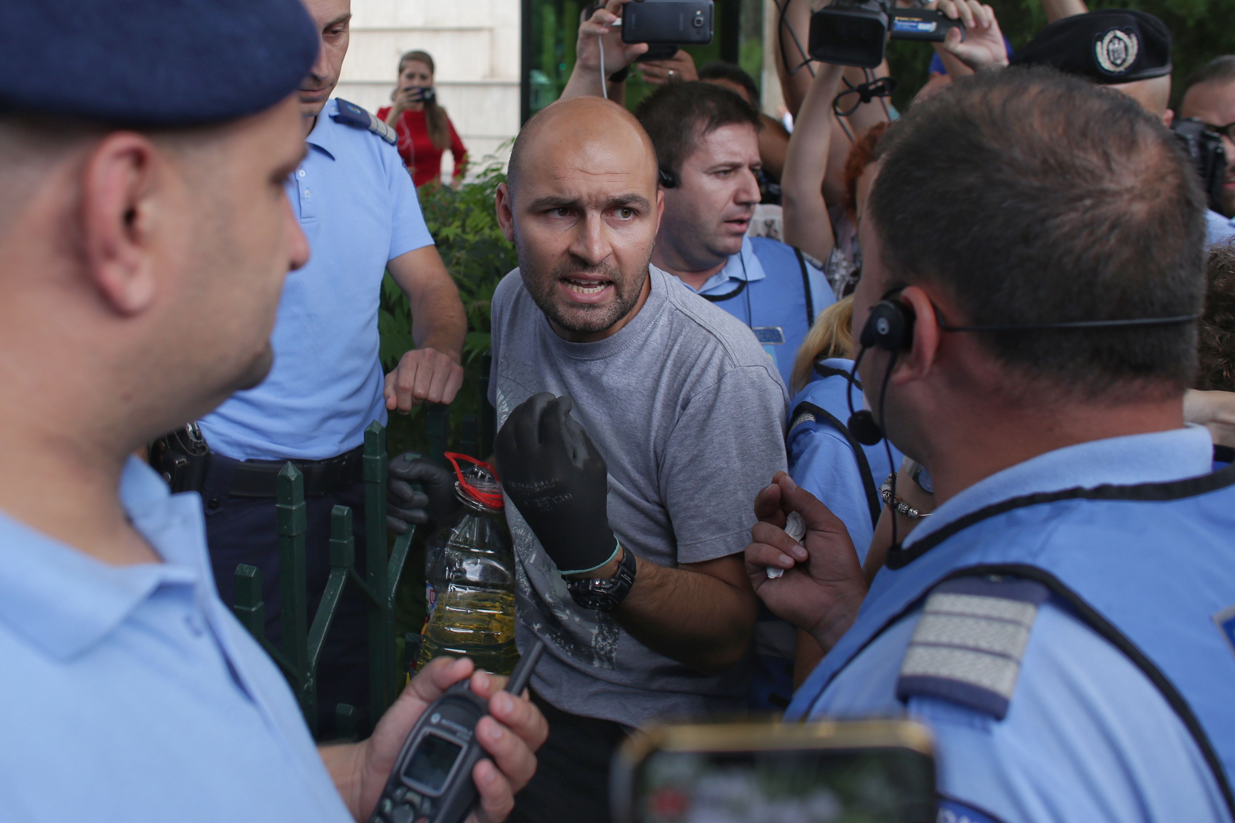 UPDATE. Bărbatul care s-a legat cu lanțul de gardul Guvernului și avea asupra lui o sticlă de benzină a fost descarcerat si ridicat de Jandarmerie (FOTO / VIDEO)
